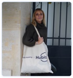 Jeune femme posant devant son domicile avec sac en tissu du pressing Ă domicile Hublo